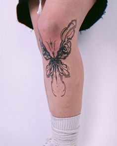 a woman's leg with a butterfly tattoo on her left leg and white socks