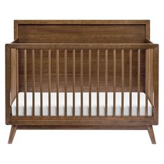 a wooden crib with white sheets on the bottom and sides, against a white background