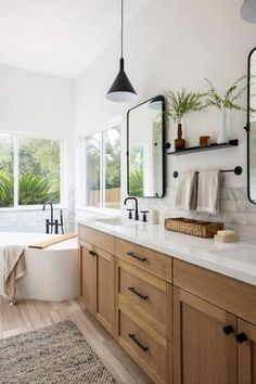 a bathroom with two sinks, mirrors and a bathtub in the middle of it