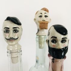 three glass bottles with fake heads in them