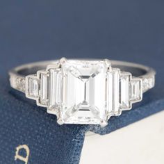 an emerald cut diamond ring with baguets on top