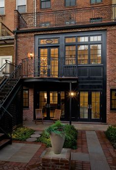 an outside view of a house with stairs leading up to the second floor and another building in the background