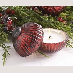 a red candle sitting next to a christmas decoration