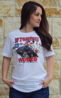 Wyoming Rodeo Tee by Original Cowgirl Clothing.The Wyoming Rodeo Tee, back in the day when a rodeo was 25 cents! You are sure to fall in love with this cool vintage style, bucking horse and wildflowers. Easy to pair the tee with vintage jeans, boots, and jacket. This updated essential unisex tee fits like a well-loved favorite, featuring a crew neck, short sleeves, and is designed with superior airlum combed and ring-spun cotton.Details: Unisex sizing--X-Small to 4-XL sizing 4.2 oz., 100% combed Cowgirl Clothing, Bucking Horse, Wildflower Design, Jeans Boots, Cowgirl Outfits, Fitted Tee, Iron Decor, Cool Vintage, Vintage Jeans