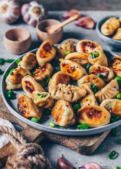 some dumplings are sitting on a plate with chopsticks and other food items