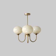 three light chandelier with white glass balls hanging from it's brass frame