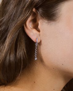 These dainty hoops are perfect for anyone who loves adding extra flair to their look! Shine and sparkle with these earrings that are studded with CZ stones and feature a dangling CZ stone charm. Materials: Rhodium plated brass, cubic zirconia Features: 1.5" drop, 0.5" hoop, 0.1" width, 3mm & 1mm CZ stones, Lead & Nickel free, friction latch Silver Dangle Hoop Earrings With Prong Setting, Sparkling Stones Chandelier Drop Earrings, Dangle Cubic Zirconia Diamond Earrings, Cubic Zirconia Dangle Diamond Earrings, Cubic Zirconia Diamond Dangle Earrings, Dangle Diamond Earrings With Sparkling Stones, Dazzling Silver Dangle Hoop Earrings, Sparkling Diamond Dangle Earrings, Cubic Zirconia Drop Earrings With Dangling Charms