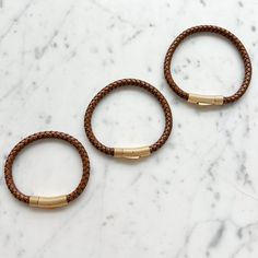 Crafted with braided natural leather and accented with gold stainless steel hardware, our Bourbon Leather Gold Men's Bracelet adds the perfect touch of sophistication to any outfit. The snap closure ensures a secure fit, and with three sizes available, there's a perfect fit for everyone. Elevate your style with this timeless accessory. Comes boxed. Available in three sizes: Small 7.5”, Medium 8.5”, Large 9.25”. Imported. Real Leather. Non toxic design. Adjustable Gold Leather Bracelet With Gold-tone Hardware, Adjustable Leather Bracelets With Gold-tone Hardware, Luxury Brown Leather Everyday Bracelet, Brown Leather Bracelets With Brass Hardware, Adjustable Leather Bracelet With Gold Clasp, Everyday Braided Leather Bracelets, Adjustable Gold Leather Bracelet With Stainless Steel Clasp, Brown Braided Bracelets For Everyday, Everyday Brown Braided Bracelets