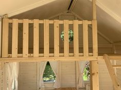 a loft bed made out of wooden planks in a room with white walls and windows