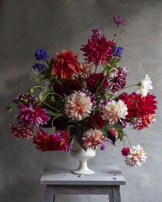 a white vase filled with lots of colorful flowers