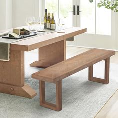 a wooden bench sitting in front of a table with wine bottles and glasses on it