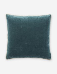 a dark green velvet pillow on a white background