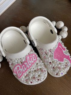 two pairs of shoes with pink and white sequins on them sitting on a table