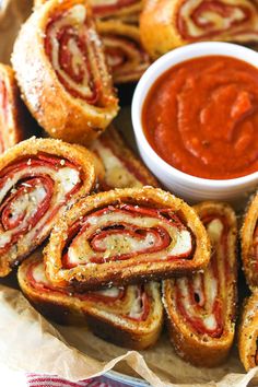 several pastries are arranged on top of each other with sauce in the bowl next to them