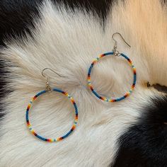 a pair of colorful beaded hoop earrings sitting on top of a white fur rug