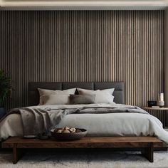 a large bed sitting under a window next to a wooden table with two vases on it