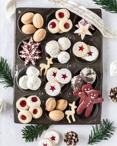 a muffin tray filled with christmas cookies and other holiday treats on top of a table