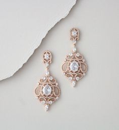 two pairs of earrings with white stones and pearls hanging from the end of each ear