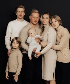 a family poses for a portrait with their two children in front of a black background