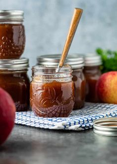 several jars filled with apple cider sitting on top of a table next to an apple