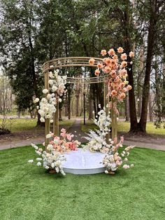 an outdoor ceremony setup with flowers and greenery on the grass, surrounded by trees