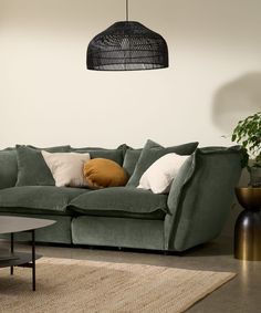 a green couch with pillows on it in a living room next to a coffee table