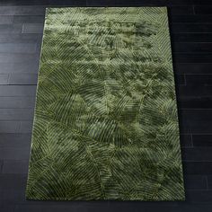 a green rug is on the floor with black tiles and wood floors in the background