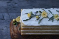 a cake with white frosting and yellow flowers on it sitting on a cutting board