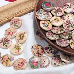 a wooden bowl filled with lots of flowers on top of a white cloth covered table