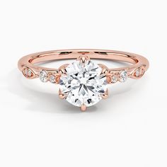 a rose gold engagement ring with an oval center stone and side stones on the band