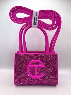 Introducing The Pink Friday Telfar. No, our latest offering is not sports related. And she's not a hat. But, she sure is stunning. This authentic azalea Telfar bag (we don't believe in fakes or bootlegs in this house) is a first of its kind and encrusted with thousands of the highest quality matching rhinestones (we don't cut corners in quality either) to ensure show stopping, attention grabbing sparkle (it's kinda our thing). Each bag is like its namesake, a true original. And for us, dare we even say the Pinkprint.  As many Telfar fans will know, it's not every day these bags are available and it could be a long time before this color is in stock again. This bag is a one-of-one and once she's gone, she's gone. Original dust bag included. Please be aware before purchasing: for maximum dur Azalea Telfar Bag, Dubai Ideas, Telfar Bags, Telfar Bag, Trendy Purses, My Style Bags, Sacs Design, Luxury Bags Collection, Handbag Essentials