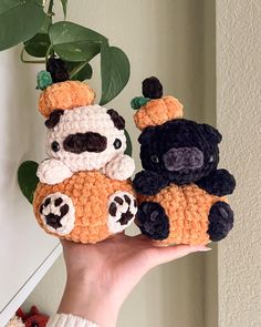 two crocheted stuffed animals sitting next to each other in front of a plant