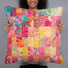 a woman holding up a colorful patchwork pillow