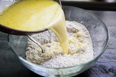 a person pouring batter into a bowl filled with flour