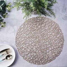 a place setting with plates, silverware and greenery on a tablecloth that has been woven onto it