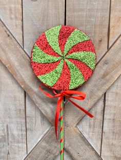 a candy cane with red and green sprinkles on it sitting in front of a wooden door