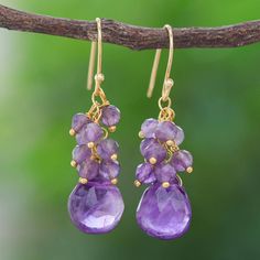 Accented with shimmering gold a cluster of purple gemstones sparkle on Arshad Ullah's dangle earrings. Thai artisans thread the gems by hand suspending a large faceted amethyst from a cluster of petite amethyst stones. 18k gold-plated sterling silver hooks give the pair a luxe appearance. Purple Drop Chandelier Earrings As Gift, Gold Amethyst Long Drop Earrings, Purple Amethyst Earrings With Dangling Beads, Purple Gemstone Chandelier Drop Earrings, Purple Gemstone Chandelier Earrings, Amethyst Drop Earrings With Dangling Beads, Gold Amethyst Drop Earrings, Purple Wire Wrapped Chandelier Drop Earrings, Purple Gemstone Accented Dangle Earrings