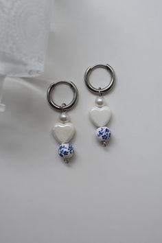 The Porcelain Heart Earrings include a white porcelain heart, a blue and white floral bead, and a simple pearl. These earrings are handmade and filled with love! Color - Blue, White, & Silver Material - Stainless Steel & Porcelain Measurements - Hoop 0.5 Inches with a 1.75 Inch drop Porcelain Heart, Silver Gold Necklace, Locket Bracelet, Simple Pearl, Porcelain Jewelry, Blue And White Floral, Pretty Jewelry, Through The Looking Glass, White Earrings