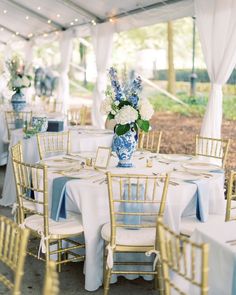 tables set up with blue and white linens for an outdoor wedding reception under a tent