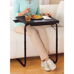 a woman sitting on a couch eating and drinking from a glass in front of her