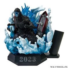 a godzilla figurine is on display in front of a black stand with blue and white foam