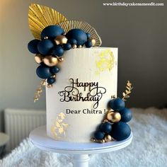 a birthday cake decorated with blue and gold decorations on top of a white tablecloth