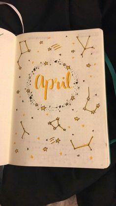 an open notebook with the word april written in gold on it and stars all around