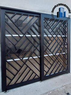 an iron gate with geometric design on the side of a building in front of a window