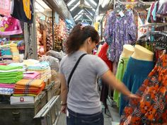 a woman is shopping at an outdoor market with many colorful items on display and in front of her