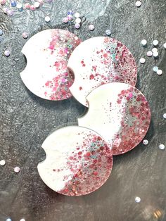 three white and pink heart shaped plates sitting on top of a black table covered in confetti