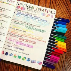 an open notebook with colorful writing on it next to colored crayons and markers