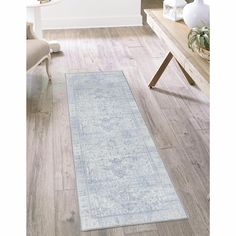 a blue rug on the floor in a living room with white walls and wooden floors