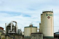 an industrial area with several large tanks and some buildings in the background on a cloudy day