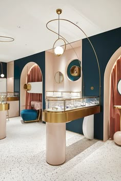 the interior of a jewelry store with pink and blue walls, gold accents and round mirrors